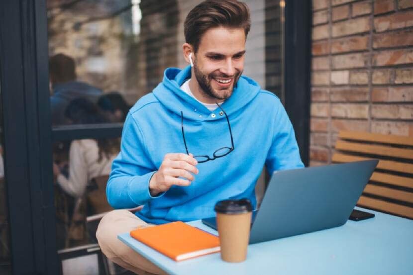 Man met blauwe hoodie zit achter zijn laptop te werken